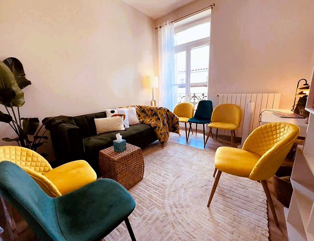 A welcoming consulting room with green and yellow chairs arranged for conversation.