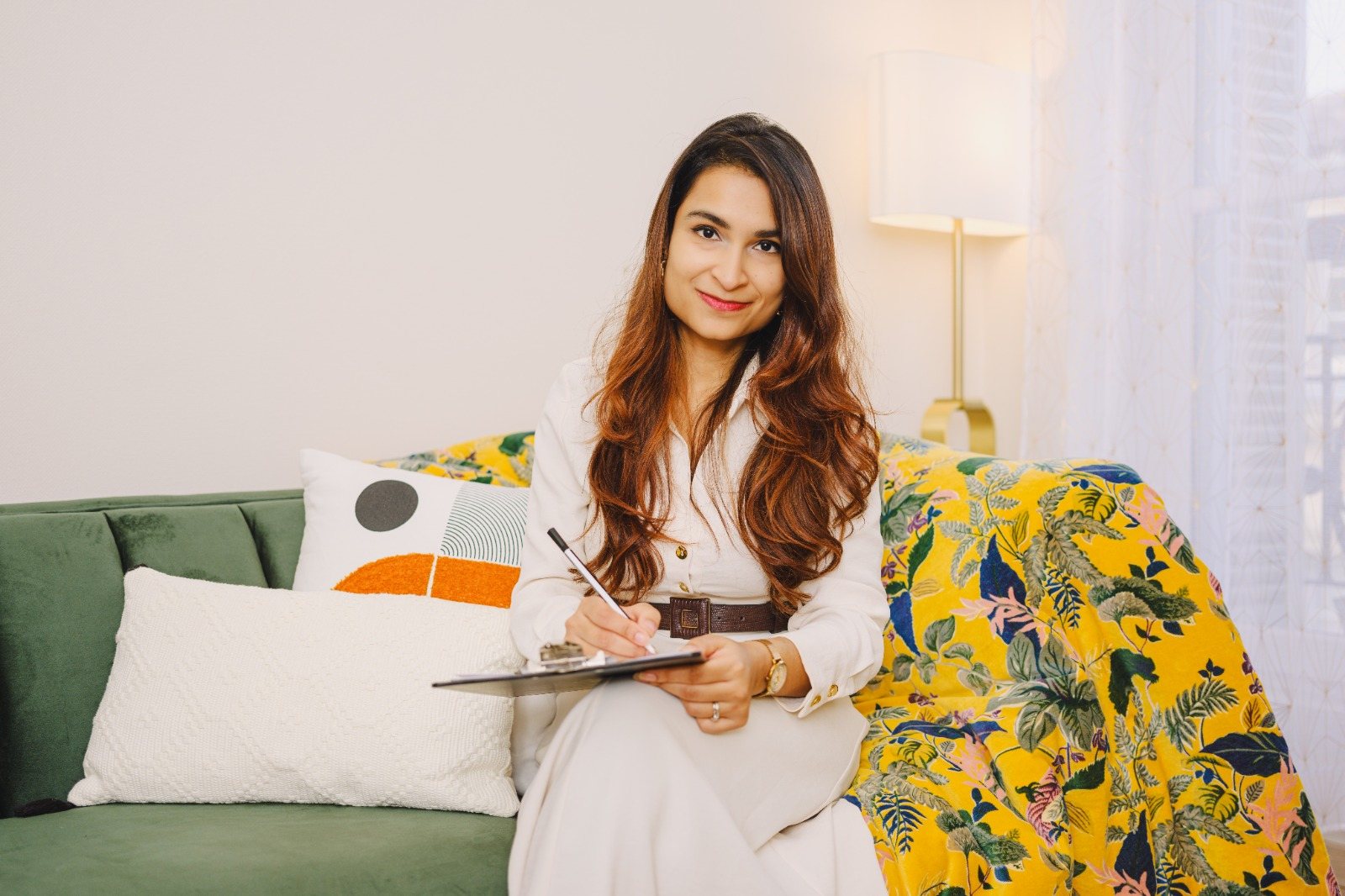 Dr Sunayana Naturé Baruah seated with a clipboard in a calm consulting room.